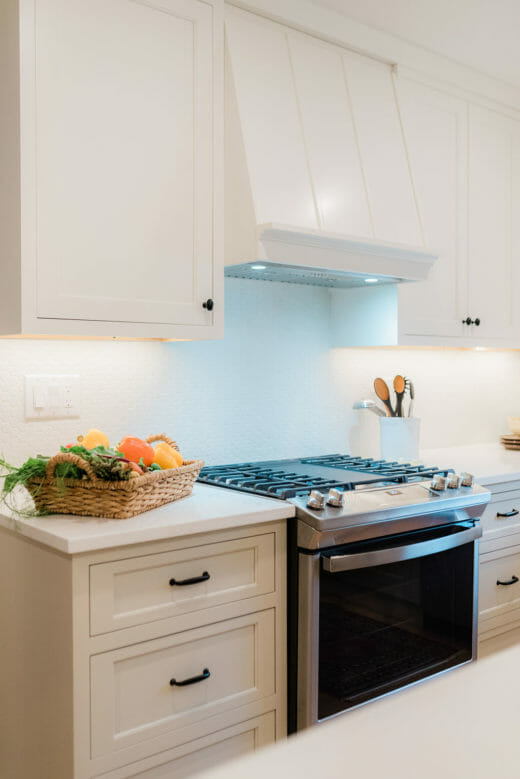 Charleene's-Houses-MD-baltimore-towson-kitchen-renovation-white-cabinets-black-hardware-range-hood-black-and-brass-sconce-above-sink