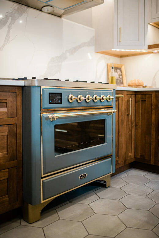 Charleene's-Houses-MD-kitchen-renovation-wood-cabinets-brass-hardware-rangehood-blue-stove-marble-backsplash