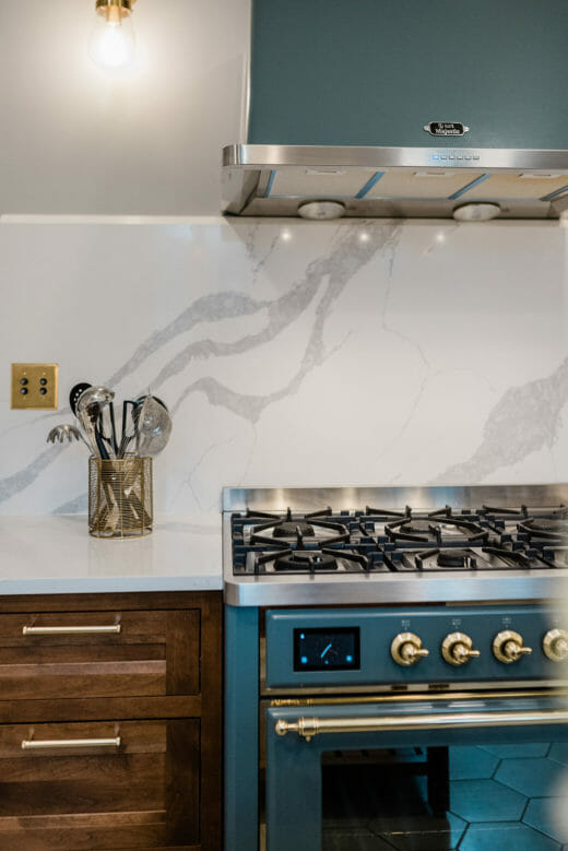 Charleene's-Houses-MD-kitchen-renovation-wood-cabinets-brass-hardware-rangehood-blue-stove-marble-backsplash