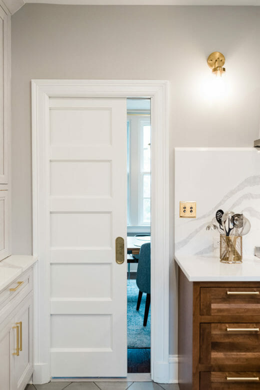 Charleene's-Houses-MD-kitchen-renovation-wood-cabinets-brass-hardware-rangehood-blue-stove-marble-backsplash-white-sliding-pocket-door